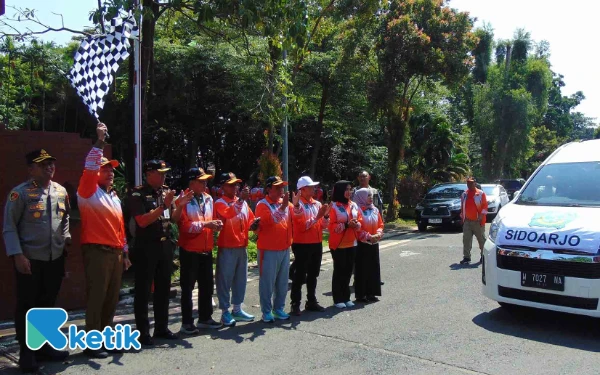 Foto Bupati Sidoarjo Subadi mengangkat bendera saat melepas atlet-atlet Sidoarjo di gerbang Pendopo Delta Wibawa pada Senin (23 Juni 2025). (Foto: Fathur Roziq/Ketik)