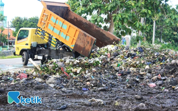 Foto Truk pengangkut sampah menumpahkan muatan kotoran dari sungai ke tempat pembuangan di Desa Krembangan, Kecamatan Taman. (Foto: Fathur Roziq/Ketik)