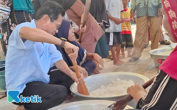 Foto Wabup Helmi mengaduk beras ditengah warga Posi-Posi (Foto: Mursal/Ketik.co.id)