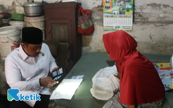 Foto Dhamroni Chudlori mengecek data kependudukan Tumilasning yang tersimpan di tas kresek. (Foto: Ketik.com)