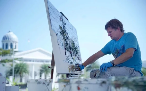 Foto Seniman asal Jerman, Christopher Lehmpfuhl, tampak khusyuk menuangkan ekspresi melalui teknik finger painting di depan Museum dan Galeri Seni SBY*Ani, Pacitan. Dengan sapuan tangan langsung di atas kanvas raksasa, ia menangkap keindahan bangunan museum dalam gaya khasnya yang ekspresif dan penuh tekstur.
Kegiatan ini menjadi bagian dari rangkaian melukis on the spot bersama seniman dari berbagai daerah dan negara.