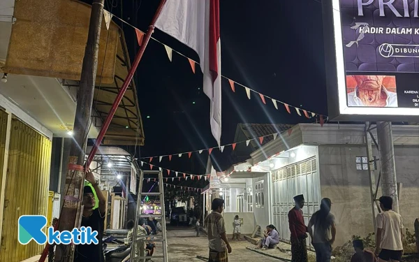 Foto Indra Maulana Arifin Tokoh Pemuda Tamberu Timur saat memasang bendera merah putih di jalan raya Desa Tamberu Timur (Foto: Mat Jusi/Ketik).