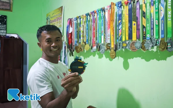 Foto Bhabinkamtibmas Sidoharjo, Aipda Gatot tengah menunjukkan ratusan medali yang ia raij raih event maraton. (Foto: Al Ahmadi/Ketik)