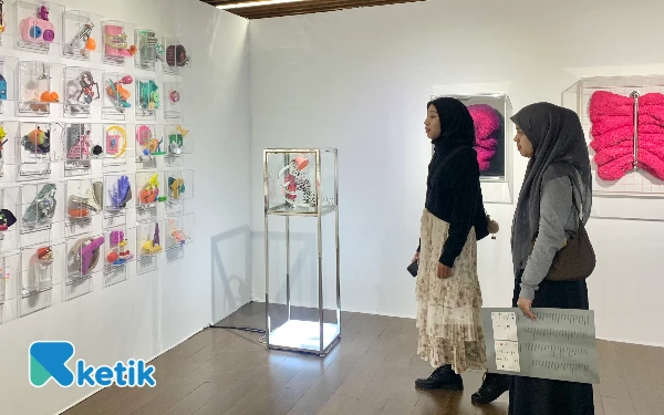 Foto Dua orang pengunjung tengah memanjakan mata dengan karya kontemporer ARTSUB 2025 (Foto: Rina/Ketik)