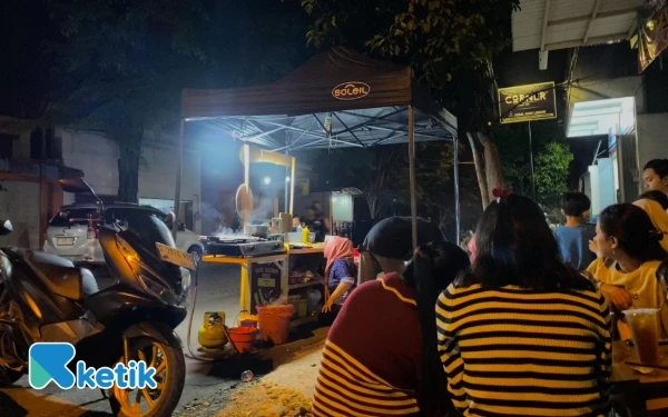Foto Suasana malam di gerai Sate Taichan Oishi, Mojosari, Minggu 21 September 2025 dipadati pengunjung yang menikmati hidangan sambil bersantai di pinggir jalan (Foto:Fika Auradewi Nazarina/Ketik)