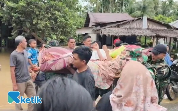 Foto Personel TNI menggotong warga lumpuh dan dievakuasi ke tempat yang lebih aman dari banjir, Nagan Raya, Kamis, 27 November 2025. (Foto: T. Rahmat/Ketik)