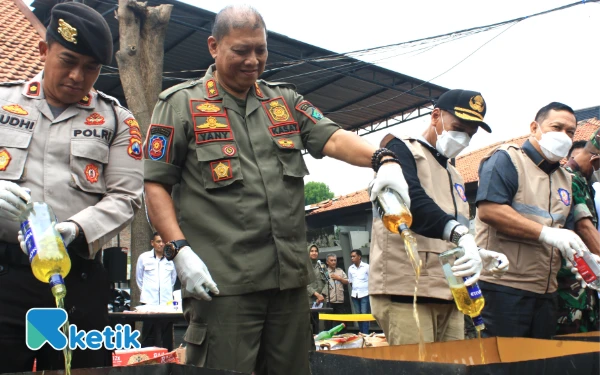 Foto Para petinggi Polresta, Satpol PP, Pemkab Sidoarjo, dan DPRD Sidoarjo menumpahkan minuman keras de dalam drum untuk dimusnahkan. (Foto: Fathur Roziq/Ketik.com)