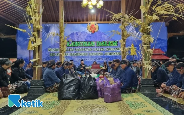 Foto Para Abdi Dalem dan warga berkumpul memanjatkan doa dalam rangkaian prosesi Labuhan Merapi. Momen ini menjadi napas kehidupan bagi Kinahrejo yang biasanya sepi sejak warga menetap di Huntap Karang Kendal. Sebuah malam di mana status sosial meluruh, menyisakan kerendahan hati manusia di hadapan Sang Pencipta dan alam. (Foto: Fajar R/Ketik.com)