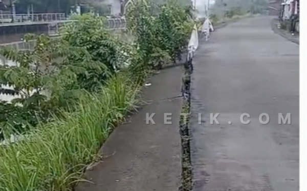 Foto Retakan di antara talud penahan tanah dan jalan beton terlihat jelas. (Foto: Fathur Roziq/Ketik.com)