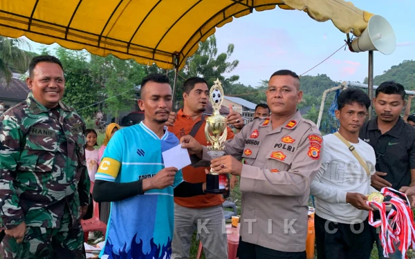 Foto Kapolsek Babahrot, Iptu Agusdi menyerahkan trofi dan dana pembinaan kepada Kapten Mancang FC, Baron dalm Turnamen Keuchik Cup Pante Rakyat di Lapangan Merdeka, Babahrot, Sabtu, 10 Januari 2026. (Foto: T. Rahmat/Ketik)