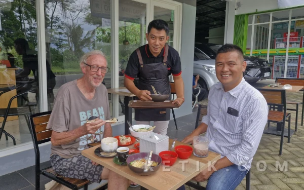 Foto Salah satu turis yang mencoba Cwie Mie di kedai Mie Pujaan Cemorokandang, Malang. (Foto: Aliyah/Ketik.com)