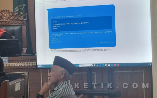 Foto Layar di ruang sidang menampilkan bukti percakapan WhatsApp antara saksi Emmy Retnosasi dan Nyoman Rai Savitri yang menyinggung koordinasi terkait daftar proposal titipan dari Raudi Akmal, Rabu, 21 Januari 2026. Di depan layar, tampak terdakwa Sri Purnomo (mengenakan peci) menyimak jalannya persidangan yang mengungkap adanya tekanan dari pihak tertentu dalam penentuan penerima dana hibah pariwisata. ( Foto: Fajar R/Ketik.com)