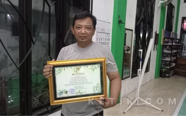 Foto Iwan Subagyo, Ketua RW 03 Kelurahan Kotalama, Kota Malang, bersama sertifikat Proklim kategori utama tahun 2025. (Foto: Nurul Aliyah/ketik.com)
