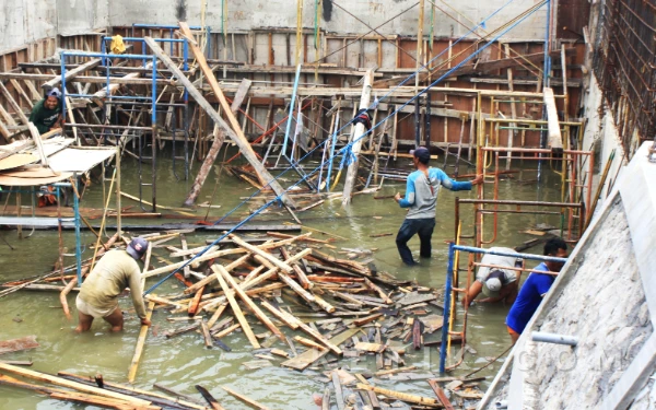 Foto Para pekerja membersihkan kayu-kayu dan material yang berada di lantai bawah proyek Rumah Pompa Kedungpeluk. (Foto: Fathur Roziq/Ketik.com)