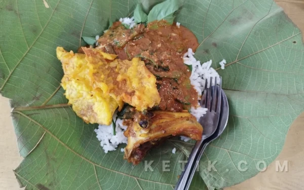 Foto Seporsi nasi pecel beralaskan daun jati lengkap dengan sayuran yang disiram bumbu pecel diatasnya. Rabu, 11 Februari 2026. (Foto : Syakira Rizki Thalita/Ketik.com)