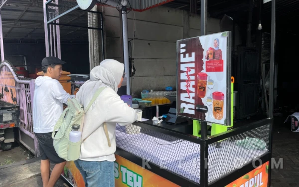 Foto Seorang pembeli terlihat memesan minuman di gerai KRAMPUL Teh & Jeruk di Desa Hulaan, Kabupaten Gresik pada 11 Februari 2026.

(Foto: Farrel Aqeel Danendra / ketik.com)
