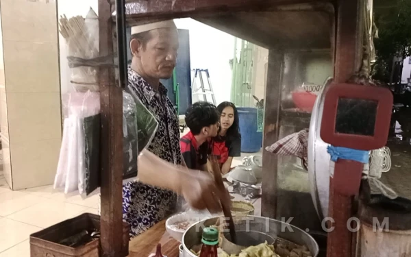 Foto Muhadi penjual bakso melayani beberapa pelanggan di area Ponpes Al-Jihad Surabaya pada Selasa malam, 10 Februari 2026. (Foto: Siska Nabilah Qothrotun Nada/Ketik.com)