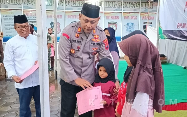 Foto Kapolsek Comal, AKP Iman Santoso memberikan santunan kepada anak yatim (Foto: Slam/ketik.com)