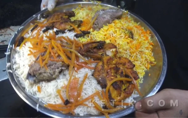 Foto Satu piring besar nasi kebuli dengan potongan daging kambing, wortel dan bumbu rempah siap disajikan kepada pengunjung. (Foto: Fitra/Ketik.com)