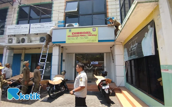 Foto Petugas Satpol PP menyegel Counter service Hand Phone VIVO di Jalan Pahlawan Kota Mojokerto (Foto: Sholahudin/Ketik)