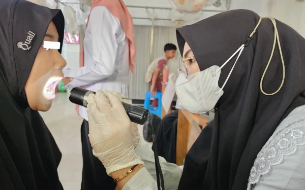Thumbnail Momen dokter gigi muda Talitha Fatimah memeriksa kesehatan gigi seorang anak. (Foto: Talitha for Ketik.co.id)