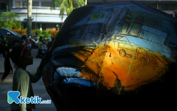 Thumbnail Tampak anak kecil melihat lukisan replika Dunia yang dibawa aktivis lingkungan melakukan aksi memperingati Hari Bumi yang jatuh pada tanggal 22 April 2025 dengan longmarch membawa replika bumi, Palembang, Selasa 22 April 2025. Dalam aksinya aktivis lingkungan ada 6 tuntutan salah satunya menuntut "Cabut izin perusahaan yang terbukti merusak lingkungan dan mencemari ruang hidup rakyak". Dalam aksi tersebut aktivis lingkungan membagikan tanaman kepada warga Palembang. Wahyu Rahmanto/Ketik.co.id.