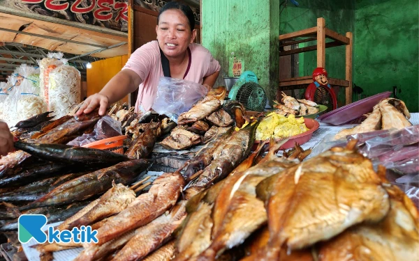 Thumbnail Seorang pedagang menunjukkan ikan asap  yang dijualnya di kawasan Pantai Kenjeran Surabaya, MInggu, 26 Oktober 2025. (Foto: Fiqih Arfani/ketik.com)