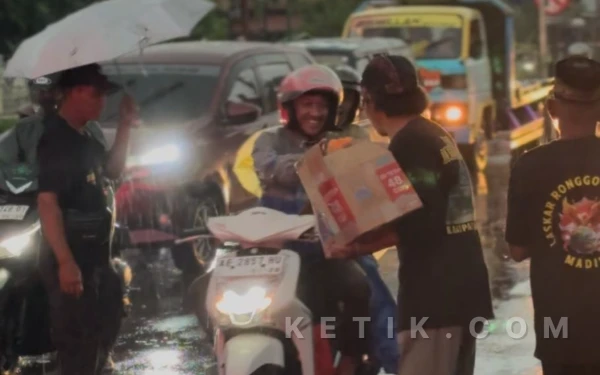 Foto Walaupun hujan, Laskar Ronggo Djoemeno tetap semangat membagikan takjil kepada pengendara yang melintas pada Minggu, 15 Maret 2026. (Foto: Angga/Ketik).