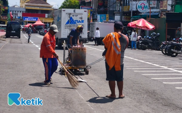 Thumbnail Pekerja sedang memberikan tanda tempat parkir sepeda motor di Alun Alun Kota Batu. (Foto: Sholeh/Ketik.com)