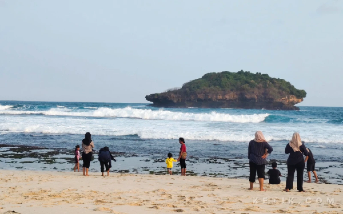 Foto Wisatawan menikmati suasana sore sambil bermain di bibir pantai kawasan Pantai Srau, Kabupaten Pacitan.