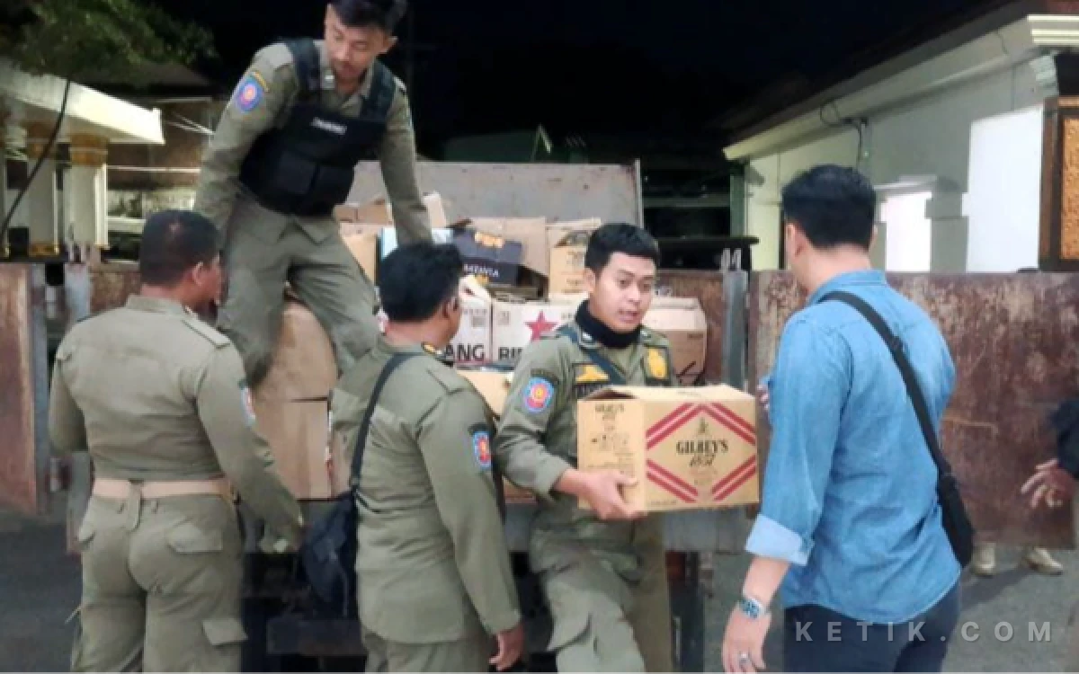 Foto Anggota Satpol PP Sidoarjo menurunkan ratusan botol miras dari truk hasil razia di salah satu toko di Kecamatan Kota Sidoarjo pada Sabtu malam (1 Agustus 2026). (Foto: Fathur Roziq/Ketik.com)
