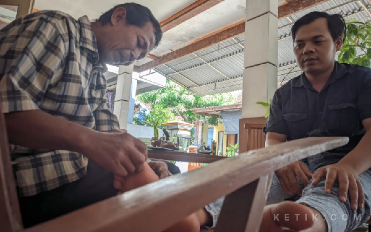 Foto Proses terapi pijat saraf oleh Heru menggunakan tanduk kerbau kepada pasien, Rojihan di rumah praktiknya di Lingkungan Gantung Kulon, Pacitan, Rabu, 20 Mei 2026.