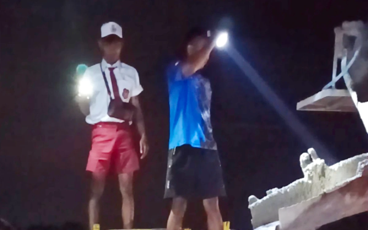 Foto Seorang pemuda menggunakan seragam SD saat pengecoran malam hari dalam kegiatan TMMD ke-128 di Desa Slempit, Kecamatan Kedamean, Kabupaten Gresik. (Foto: ITH for Ketik.com)