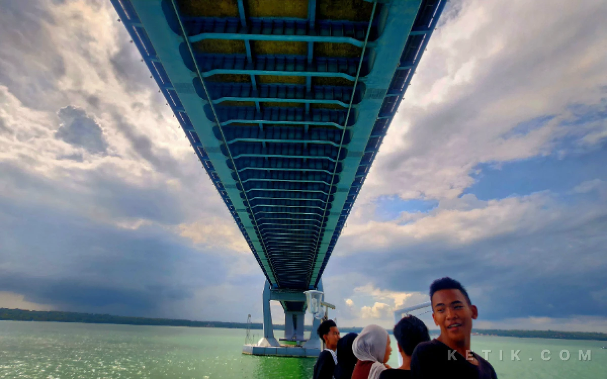 Foto Sejumlah penumpang KM Kirana VII mengabadikan momen saat melintas di bawah Jembatan Suramadu pada Minggu, 3 Mei 2026. (Foto: Fiqih Arfani/ketik.com)